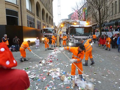 AWB Wagen mit Müllsauger und mehre AWB Mitarbeitende der Stadtreinigung mit Besen reinigen an Karneval die Straße nach dem Karnevalsumzug. 